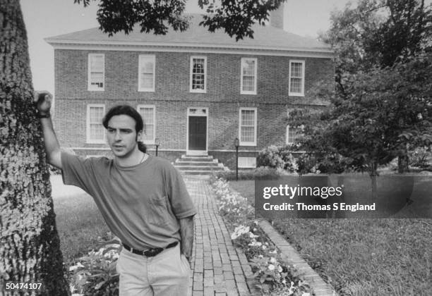 Steve Wilson, the son of murder victim, opthalmologist Dr. Jack Wilson, sadly leaning against tree in front of two-story brick house where his dad...