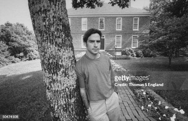 Steve Wilson, the son of murder victim, opthalmologist Dr. Jack Wilson, sadly leaning against tree in front of two-story brick house where his dad...