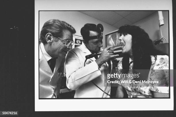 Otolaryngologist Dr. Robert Ossoff, head of Vanderbilt Univ. Voice Center, wearing a light reflector headband as he examines C/W singer Kathy...