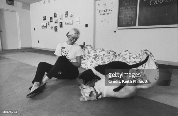 Yuppie Puppie Day Care owner Barbara Bocci smiling as she sits on the floor, watching two wrestling puppies left at the center by their owners who...