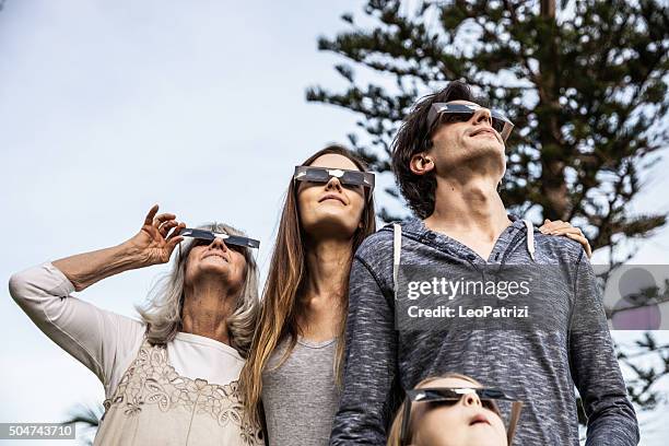 familia mirando en eclipse solar usando gafas de sol - eclipse fotografías e imágenes de stock