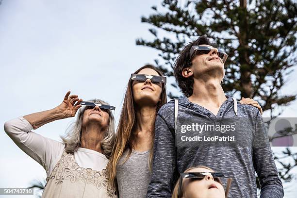 family looking at solar eclipse using solar glasses - zonsverduistering stockfoto's en -beelden
