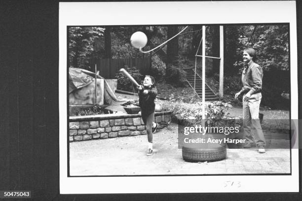 Author John Gray w. Daughter Lauren who is swinging bat at tetherball in their backyard. Marin County.