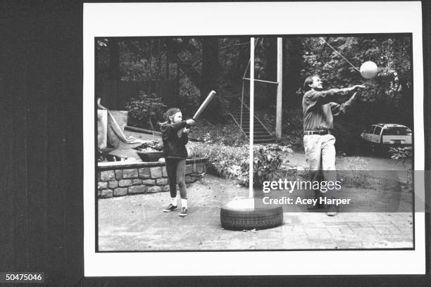Author John Gray w. Daughter Lauren who is swinging bat at tetherball in their backyard. Marin County.