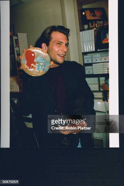Actor Christian Slater holding up a collectors plate w. A scene fr. The animated Bugs Bunny episode Hair Raising Hare at opening of Warner Bros....