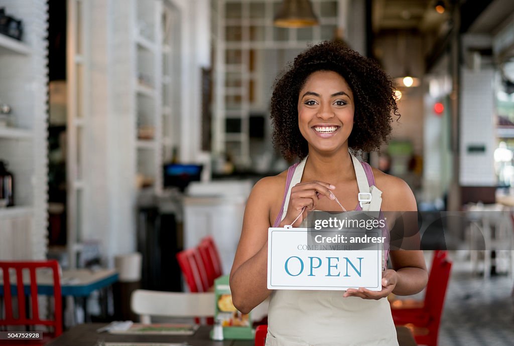 Waitress holding an open sign at a restaurant