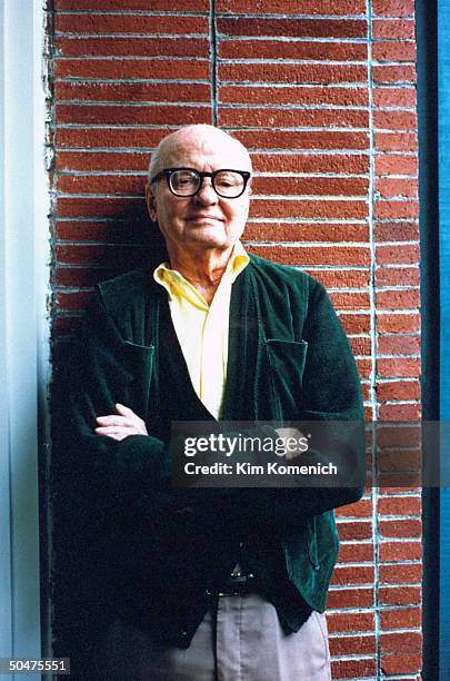 Author Jack Finney alone poised by brick wall, at home.