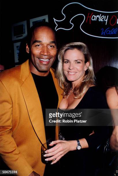 Football star turned actor O.J. Simpson w. His arm around wife Nicole at the opening of the Harley Davidson Cafe.