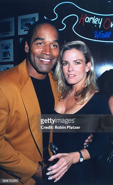 Football star turned actor O.J. Simpson with his arm around wife Nicole at the opening of the Harley Davidson Cafe.