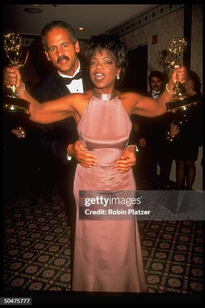 Stedman Graham hugging fiancee, talk show host Oprah Winfrey, as she shows off the two Emmy awards she won for best TV talk show & best host at the...