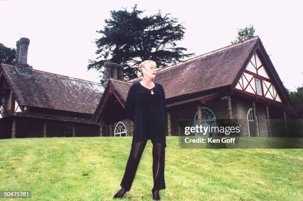 Singer Marianne Faithfull wearing black tunic & lace leggings as she poses on lawn outside her 19th C. Cottage.