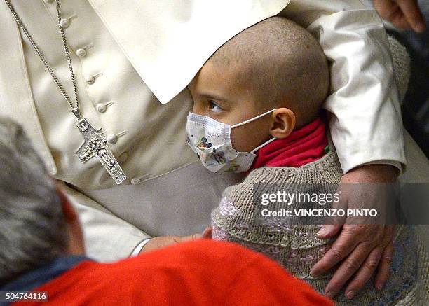 Pope Francis embraces a sick child during his weekly general audience on January 13 in Paul VII hall at the Vatican. / AFP / VINCENZO PINTO