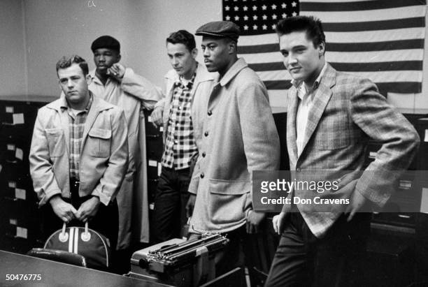 Rock & roll singer Elvis Presley in checkered sport coat, standing w. 4 other inductees as they wait to be processed at Army induction station.