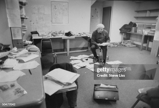 Socialist congressional cand. Bernie Sanders reading mail in paper-covered campaign office in Burlington.