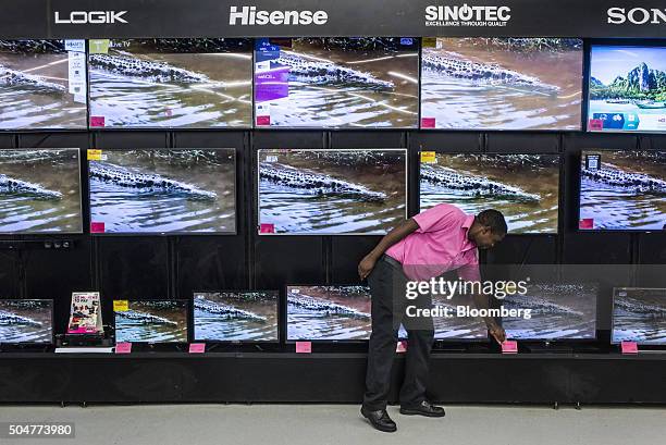 An employee adjusts a price sign on a display of flat screen televisions for sale in a Game supermarket, operated by Massmart Holdings Ltd., at the...