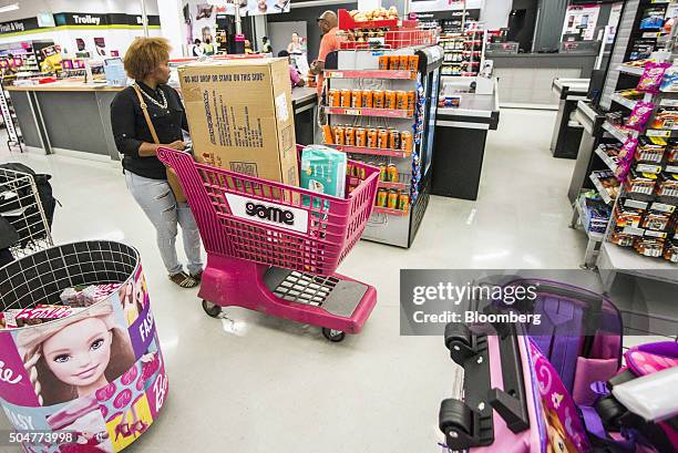 Shopper pushes a shopping cart loaded with goods past the check out counters of a Game supermarket, operated by Massmart Holdings Ltd., at the...