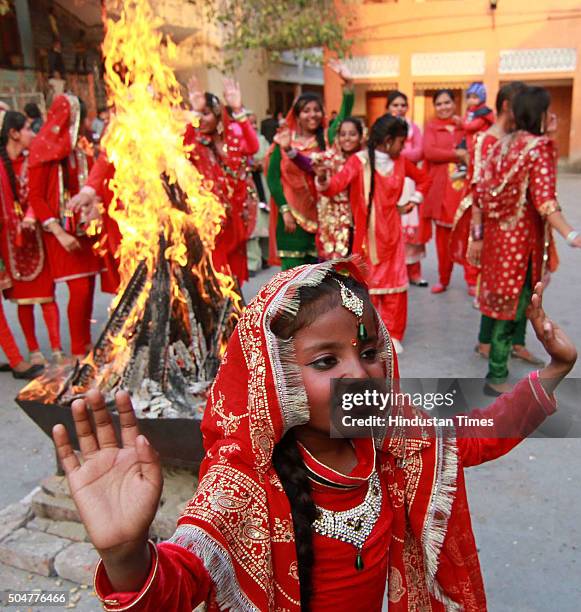 Girls in traditional attire dance around a bonfire as they celebrate Lohri festival on January 13, 2016 in Jammu, India. Lohri celebrates the harvest...