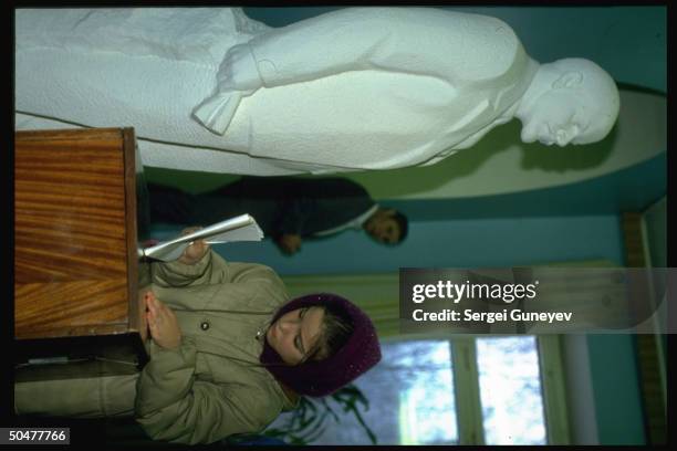 Girl inserting ballot in box, watched over by Lenin statue, in 1st democratic parliamentary elections at 55th district polls.