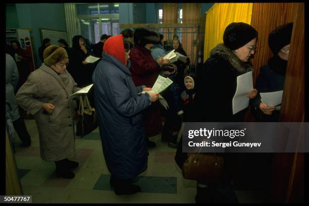 Voters waiting, scanning ballot choices, before casting ballots in 1st democratic parliamentary elections at 55th district polls.