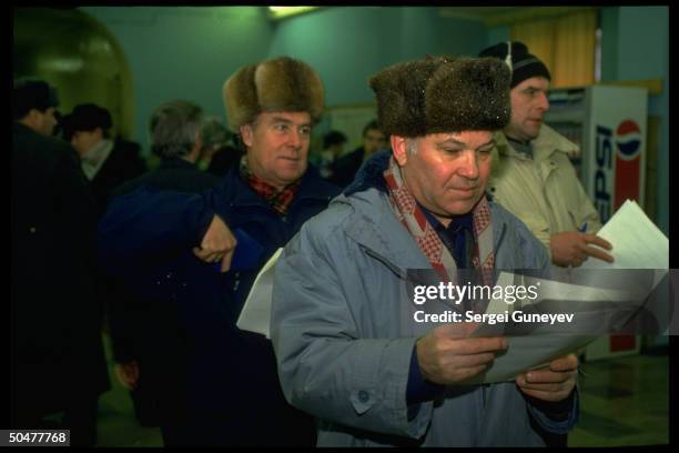 Voters waiting, scanning ballot choices, before casting ballots in 1st democratic parliamentary elections at 55th district polls.