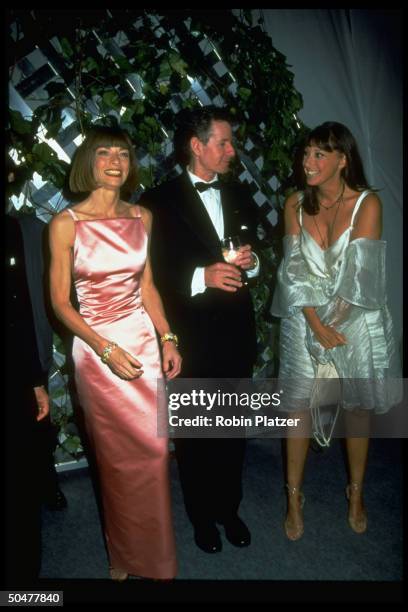 Ed. Anna Wintour, wearing shiny pink dress by Calvin Klein, w. Fashion designers Calvin Klein & Donna Karan at unident. Benefit.