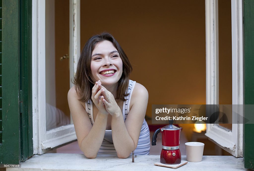Young woman having coffee at the open window