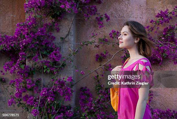 young woman walking past bougainvillea - woman wearing purple dress stock pictures, royalty-free photos & images