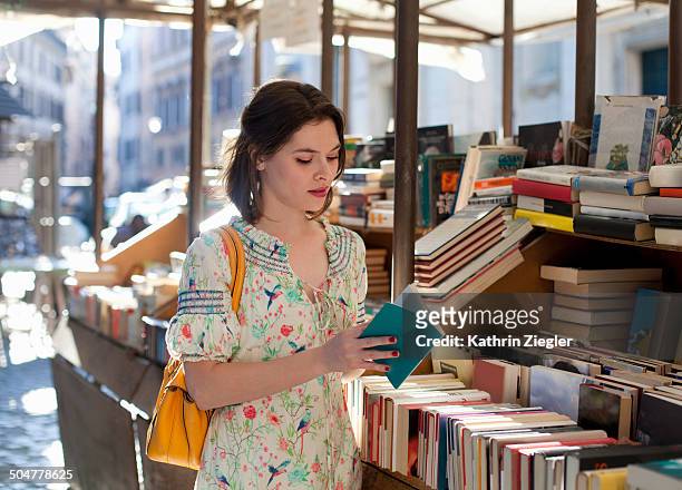 young woman flipping through book at bookstall - book store stock-fotos und bilder