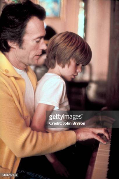 Actor Clint Eastwood playing piano while son Kyle sits on his lap at his home.