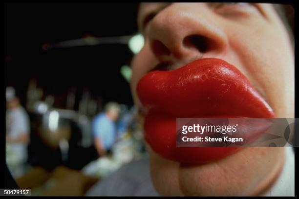 Closeup of businessman Ben Shepherd wearing pair of red wax lips made by his co., Challenger Candy.