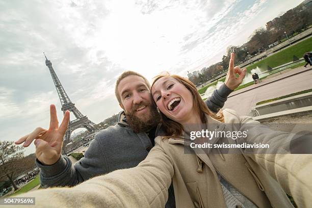 young couple take selfie portrait at eiffel tower, paris - couple paris tour eiffel trocadero stockfoto's en -beelden