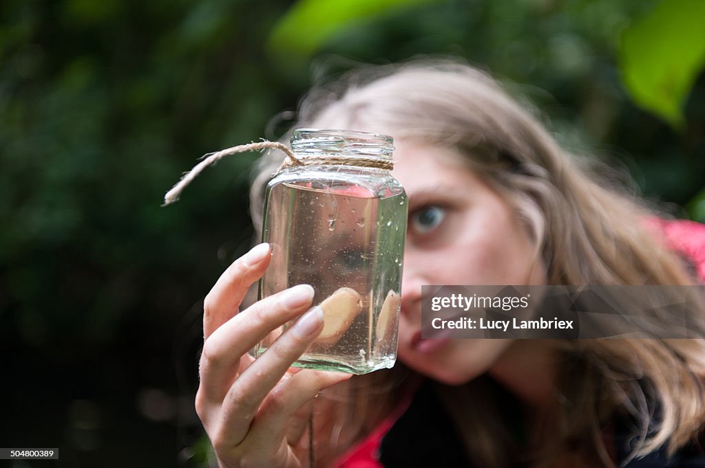 Young woman looking at a jar of ditchwater