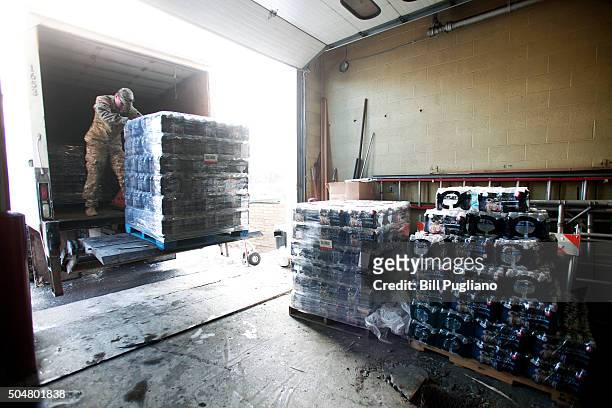 Michigan National Guard Staff Sergeant William Phillips of Birch Run, Michigan, helps unload pallets of bottled water at a Flint Fire Station January...