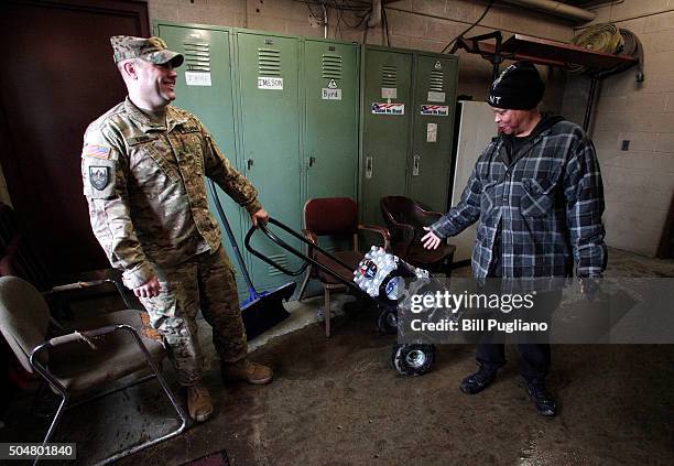 Michigan National Guard Staff Sergeant Steve Kiger of Beaverton, Michigan, helps Christine Brown of Flint, Michigan take bottled water out to her car...