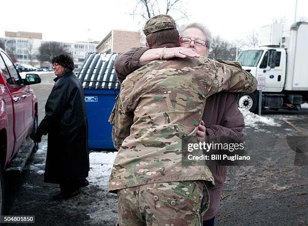 Michigan National Guard Staff Sergeant William Phillips of Birch Run, Michigan, gets hug from from a Flint resident after helping her take bottled...