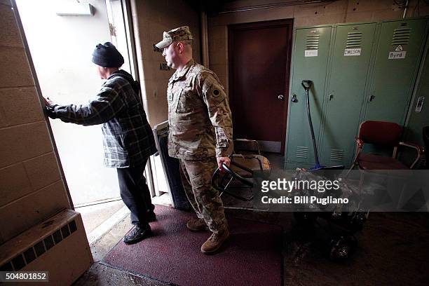 Michigan National Guard Staff Sergeant Steve Kiger of Beaverton, Michigan, helps Christine Brown of Flint, Michigan take bottled water out to her car...