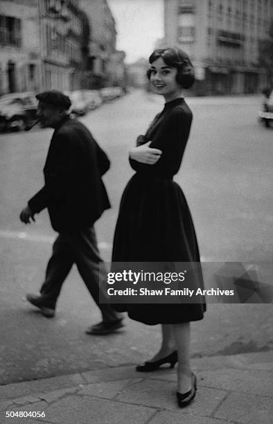 Audrey Hepburn poses in a black dress on the street in 1957 in Paris, France.