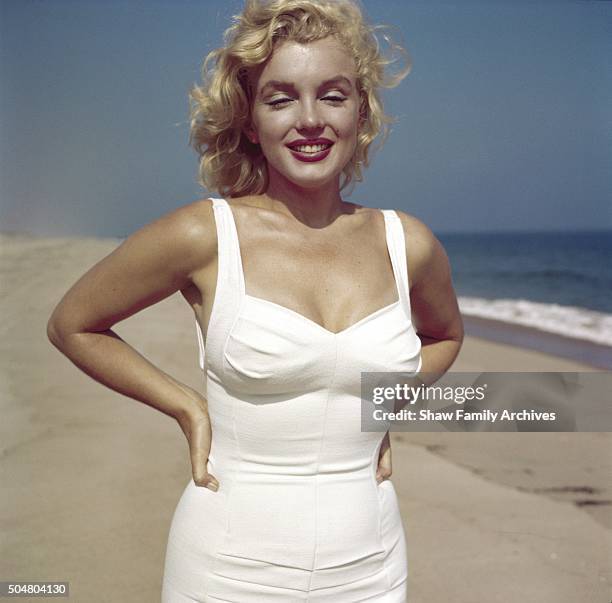 Marilyn Monroe poses with her hands on her hips on the beach in 1957 in Amagansett, New York.