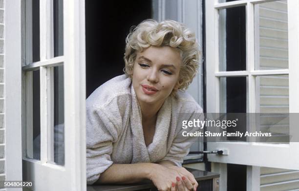 Marilyn Monroe leaning out of a window in her bathrobe in 1954 during the filming of "The Seven Year Itch" in New York, New York.