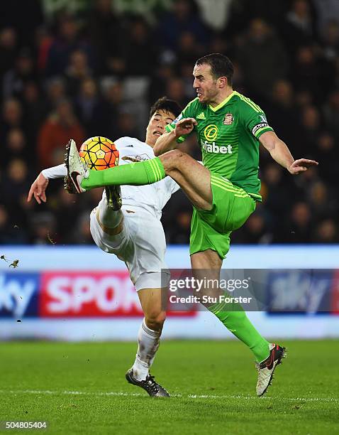 John O'Shea of Sunderland and Ki Sung-Yeung of Swansea City compete for the ball during the Barclays Premier League match between Swansea City and...