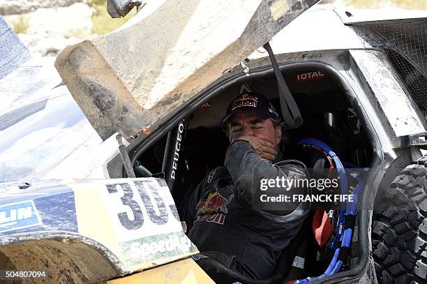 Peugeot's Spanish driver Carlos Sainz gestures inside the car after a mechanical failure during the Stage 10 of the Dakar 2016 between Belen and La...