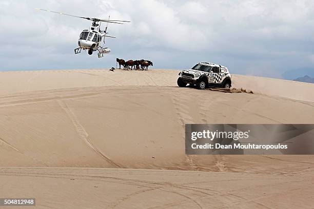 Mikko Hirvonen of Finland and Michel Perin of France in the MINI ALL4 RACING for AXION X-RAID TEAM are followed by the TV helicopter as they pass a...