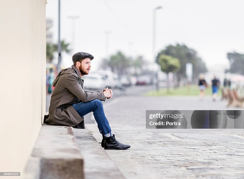 Man sitting on steps at sidewalk