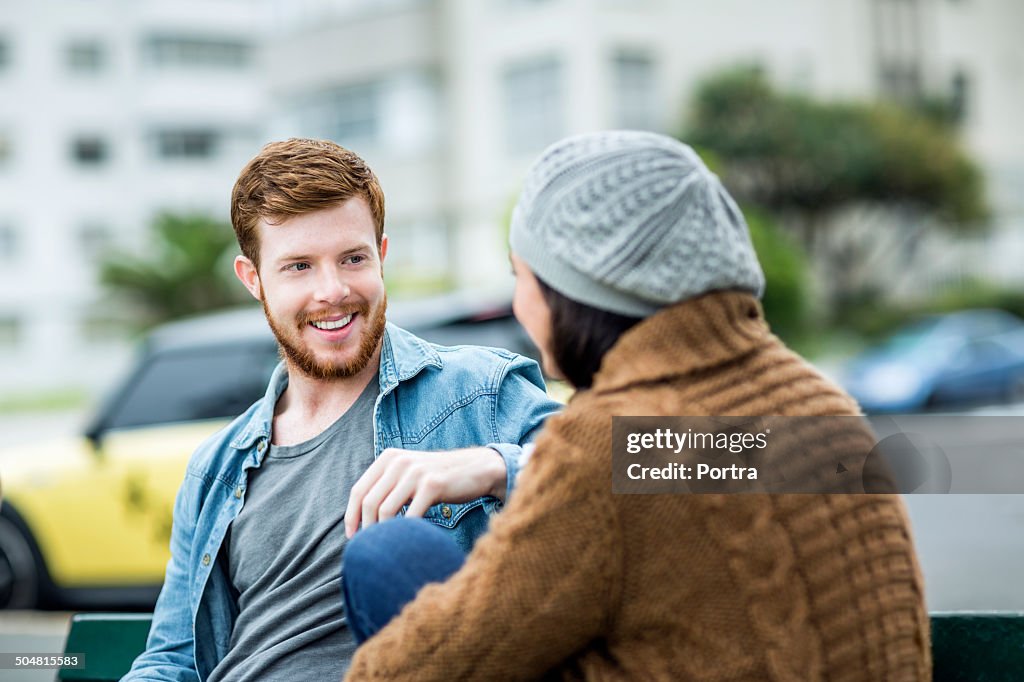 Happy man relaxing with woman on park bench