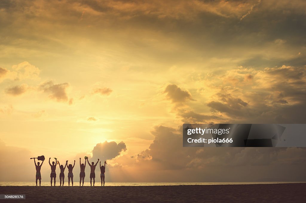 Group of friends raised arms to the sea