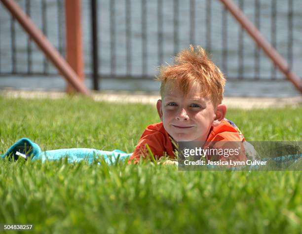 ginger haired boy relaxing on a towel by a lake - ginger lynn - fotografias e filmes do acervo