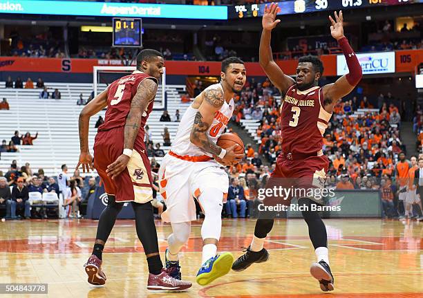 Michael Gbinije of the Syracuse Orange drives to the basket between Garland Owens and Eli Carter of the Boston College Eagles during the first half...