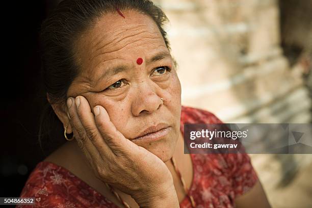 peasant woman holding head and looking up with blank expression. - india nepal stock pictures, royalty-free photos & images