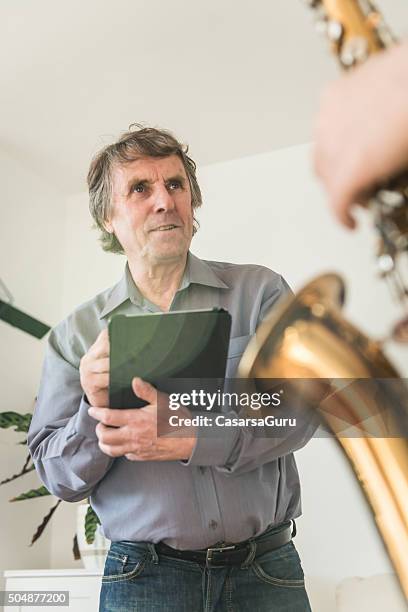 young man learning to play saxophone at home - woodwind instrument stock pictures, royalty-free photos & images