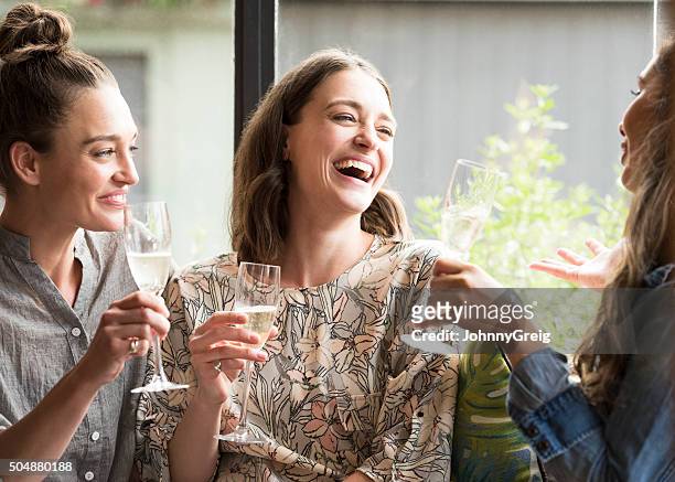 women laughing in bar with wine glasses - bar atmosphere stock pictures, royalty-free photos & images